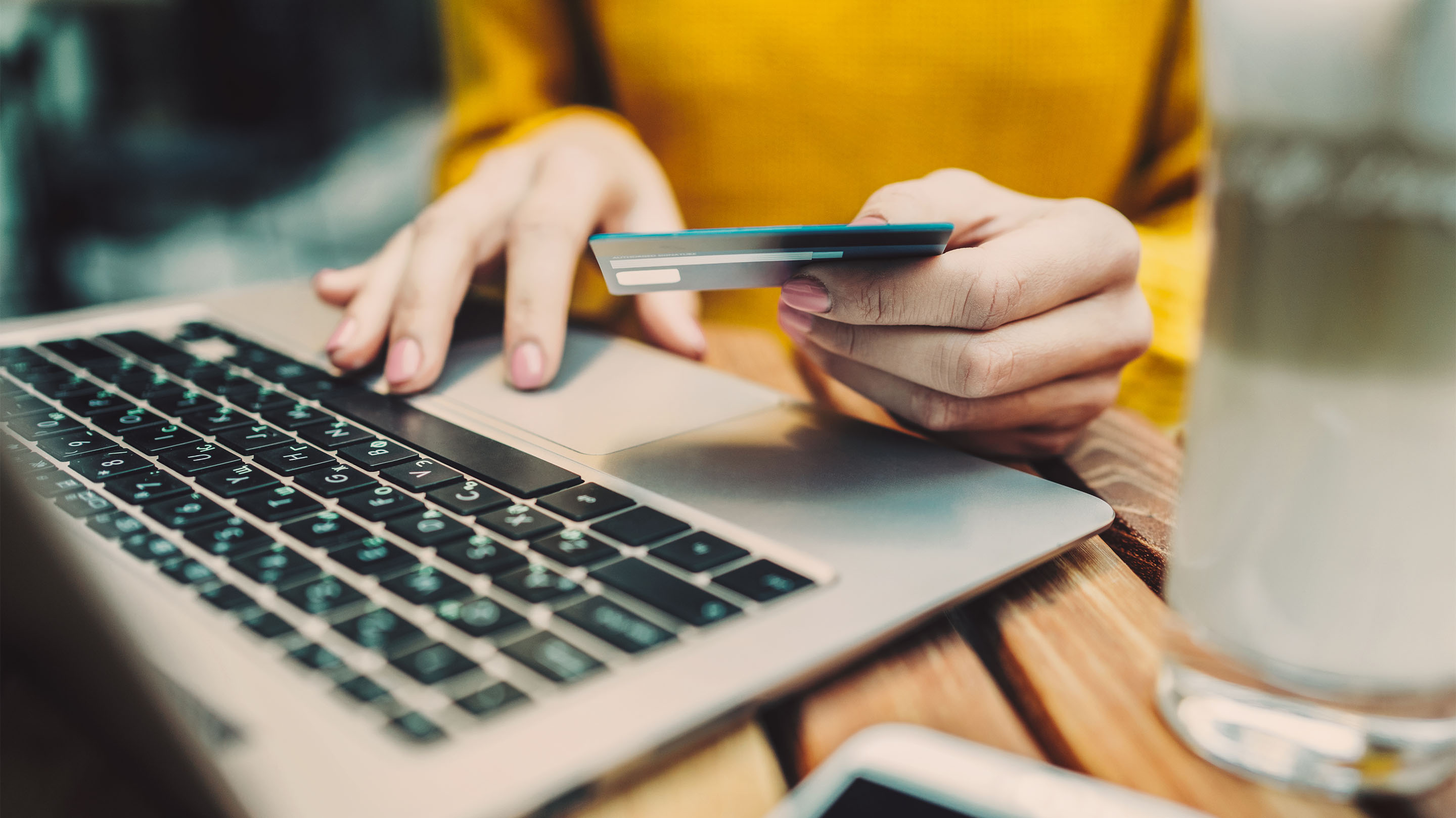 Person using a laptop with a credit card in their hand